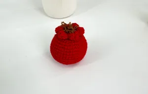 Detailaufnahme eines handgemachten Häkel-Frucht-Anhängers aus Garn, feine Strickstruktur Deko.