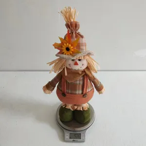 Detailed view of Thanksgiving scarecrow doll with sunflower, maple leaf and plaid hat.