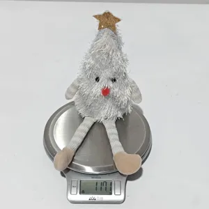Vue détaillée d'un jouet en peluche sapin de noël aux longues jambes sur une balance.
