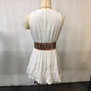 Achteraanzicht detail van witte mouwloze minijurk met kleurrijke geborduurde tailleceintuur.