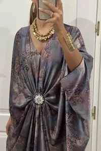 Detail of bohemian printed batwing sleeve kaftan dress with crystal brooch accent.