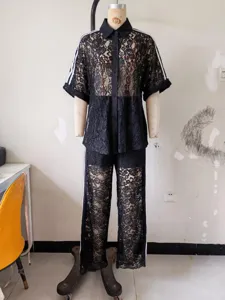 Black lace two-piece outfit detail showing short sleeve shirt and pants with white stripes.