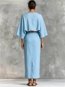 Detailed view of light blue linen two-piece set with batwing sleeves and split skirt.
