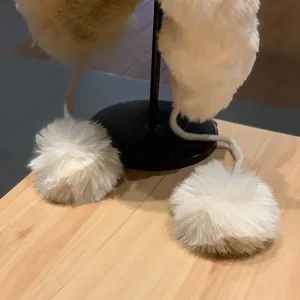 Gros plan sur le bonnet d'hiver en peluche blanche duveteux avec pompons et cache-oreilles.