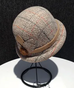 Detailed view of the retro plaid cloche hat, featuring a rolled brim, decorative band and side bow.