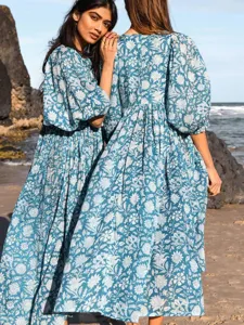 Detailed shot of floral print beach vacation dress with puff sleeves and V-neck styling.