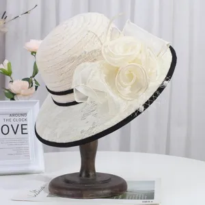 Close-up of elegant beige lace sun hat with floral decor and black trim, stylish design.