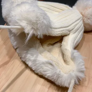 Gros plan detail du bonnet hiver peluche cache-oreilles epais, doublure polaire, blanc creme.