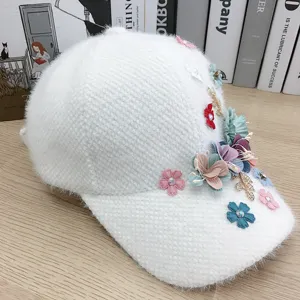 Dettaglio berretto da baseball soffice bianco, cappello caldo di peluche con fiori e strass.