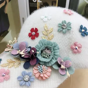 Primo piano dettagliato del cappellino da baseball bianco in peluche con fiori di stoffa e strass.