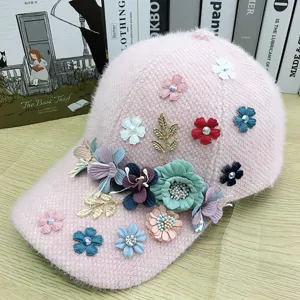 Dettaglio del cappello in peluche rosa con fiori in tessuto, strass scintillanti e foglie metalliche.