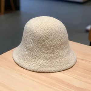 Close-up view of a cozy beige wool bucket hat resting on a wooden table, winter fashion detail.