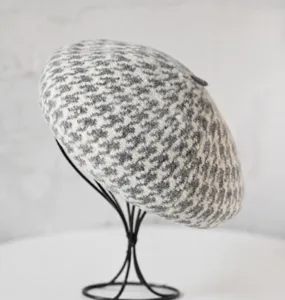 Détail de béret en laine à motif pied-de-poule gris et blanc montrant la texture tricotée.