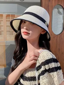 Detail view of a stylish women's hollow woven sun hat with a chic black ribbon and wide brim.