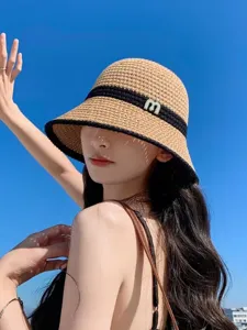 Stylish woven bucket hat for women, wide brim sun protection straw hat with elegant letter detail.
