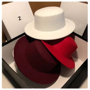 Detailed view of fashionable women flat top wool felt hats in white, red and burgundy colors.