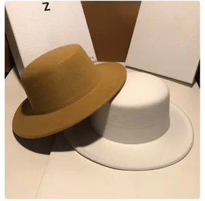 Close-up detail of stylish women's flat-top felt hats in camel and white, classic autumn winter.