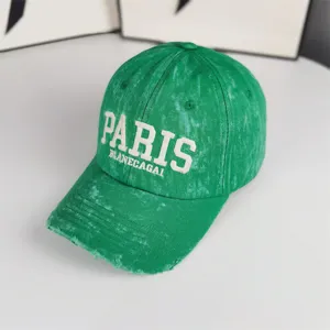 Gros plan détaillé de la casquette de baseball verte vintage usée avec lettrage brodé et visière.