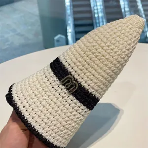 Close-up detail of the black and white knit bucket hat with metal letter accent for women.