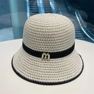 Detailed shot of women's woven straw bucket hat with black ribbon and metal m logo for summer.