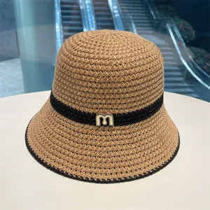 Hollow woven straw bucket hat for women with black band and shiny letter decor for sunny days.