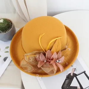 Gros plan très détaillé d'un chapeau en laine jaune avec des accents de plumes et de fleurs.