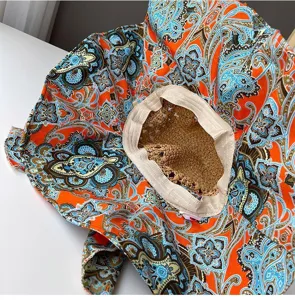Vue de détail du chapeau de soleil bohème avec imprimé cachemire orange et couronne en paille.