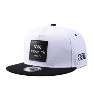 Gorra snapback de ala plana blanca y negra unisex con elegante parche de cuero y visera.