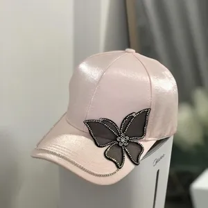 Detailaufnahme einer rosa Satin-Baseballkappe mit glitzerndem Strass-Schmetterling.