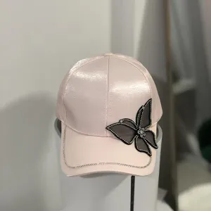 Rosa Strass Baseballkappe Detail mit atemberaubendem schwarzen Schmetterlings-Patch.