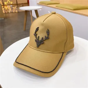 Gros plan de casquette de baseball kaki avec cerf en strass et bordure de visière scintillante.