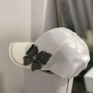 Detailansicht weiße Baseballcap mit Strass-Schmetterling, stylischer Sonnenschutzhut.