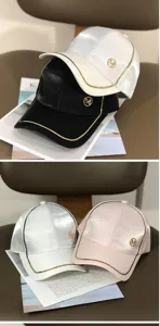 Detailansicht der modischen Damen Baseballkappe mit Metall M Logo und goldener Paspelierung.