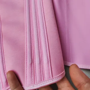 Close-up view of pink latex waist trainer showing detailed boning and fine stitching quality.