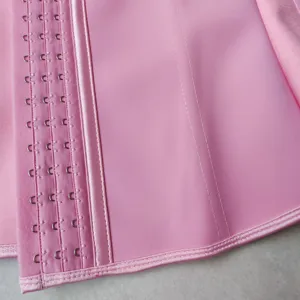 Close up detail of pink latex waist trainer featuring adjustable steel hooks and firm stitching.