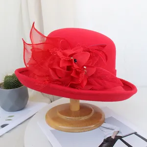 Chapeau melon en feutre de laine rouge avec fleur en filet élégante et plume automne hiver.