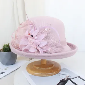 Détail de chapeau melon en feutre rose, élégant filet, décoration florale et plume, rétro.