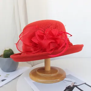 Detail de chapeau en feutre de laine rouge avec bord roule et decor de fleurs en filet.