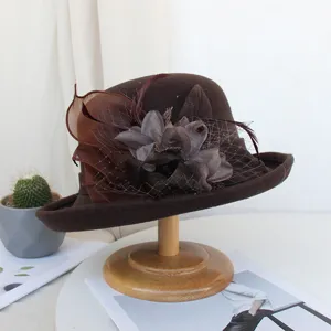 Gros plan et détail du chapeau en feutre de laine marron avec résille délicate et fleurs de plumes.