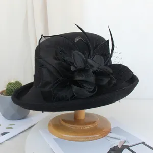 Chapeau cloche noir en feutre de laine vintage pour femme avec filet et fleur de plume.