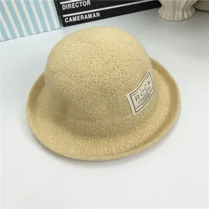 Beige Strohhut mit Rollrand und stilvollem Buchstabenaufnäher an der Seite für sonnige Tage.
