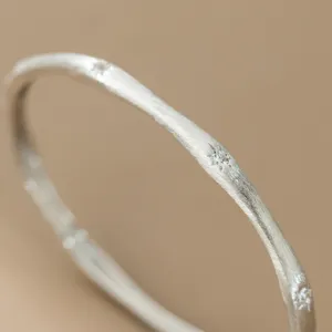Detailed close-up of a vintage brushed silver bangle featuring sparkling star-set stones.