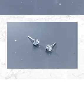 Nahaufnahme minimalistischer herzförmiger Kristall-Ohrstecker mit feinen glänzenden Details.