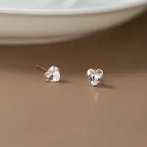 Nahaufnahme Detail von glitzernden herzförmigen weißen Kristall-Ohrringen in Roségold.