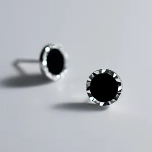 Gros plan de fines boucles d'oreilles clous minimalistes argent S925 et agate noire.