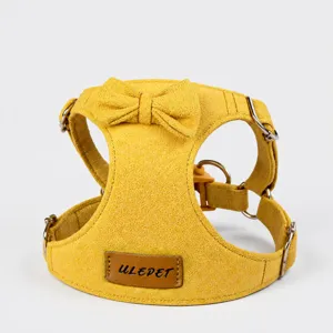 Detail view of a yellow suede pet harness featuring a cute bow and metal D-rings.