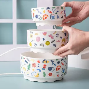 Ceramic pet constant temperature heating water bowl with colorful doodle print and power cord.