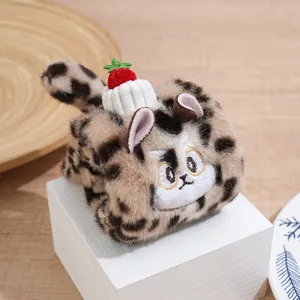 Plush cat toy detail showing soft leopard print texture, cute ears and strawberry decoration.