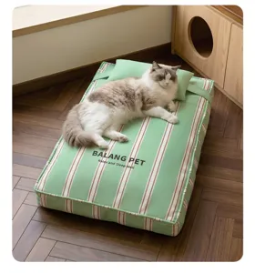 Green striped pet bed with a small pillow and cute cat lying on wooden floor detail view