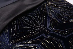 Vista detallada de tela de traje de terciopelo azul oscuro con patrones geométricos dorados.